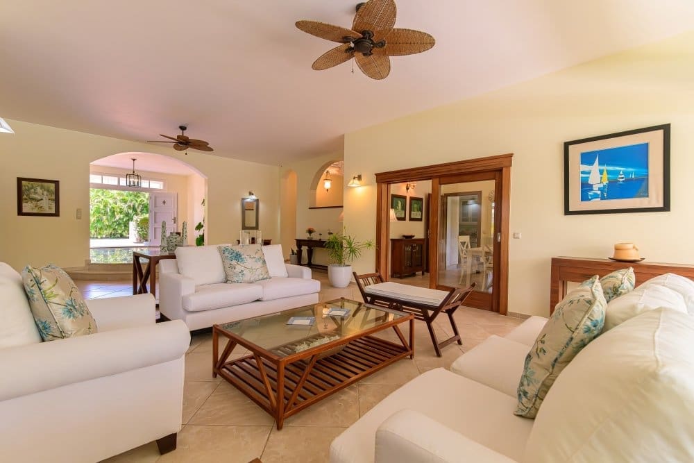 buyDRproperty Bright, airy living room with white sofas, coffee table, and tropical decor. Sosua Real Estate