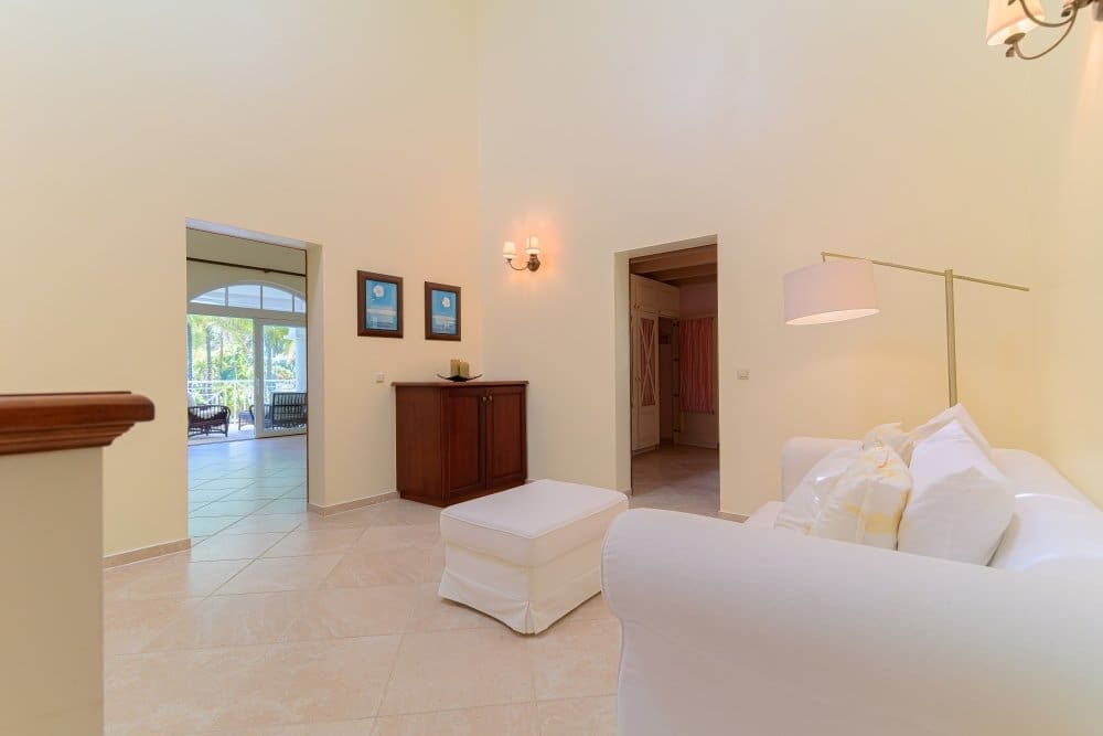 buyDRproperty Bright, airy living room with white sofa, ottoman, and doorways to other rooms. Sosua Real Estate