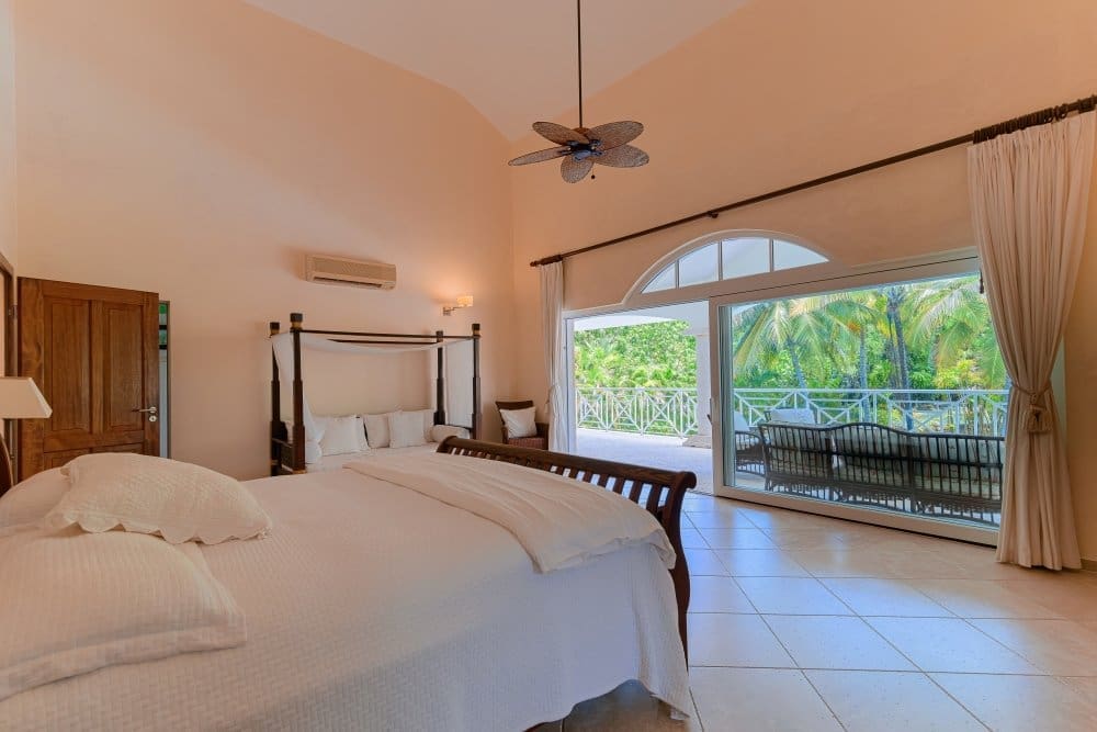 buyDRproperty Luxurious bedroom with canopy bed and balcony view of tropical palm trees. Sosua Real Estate