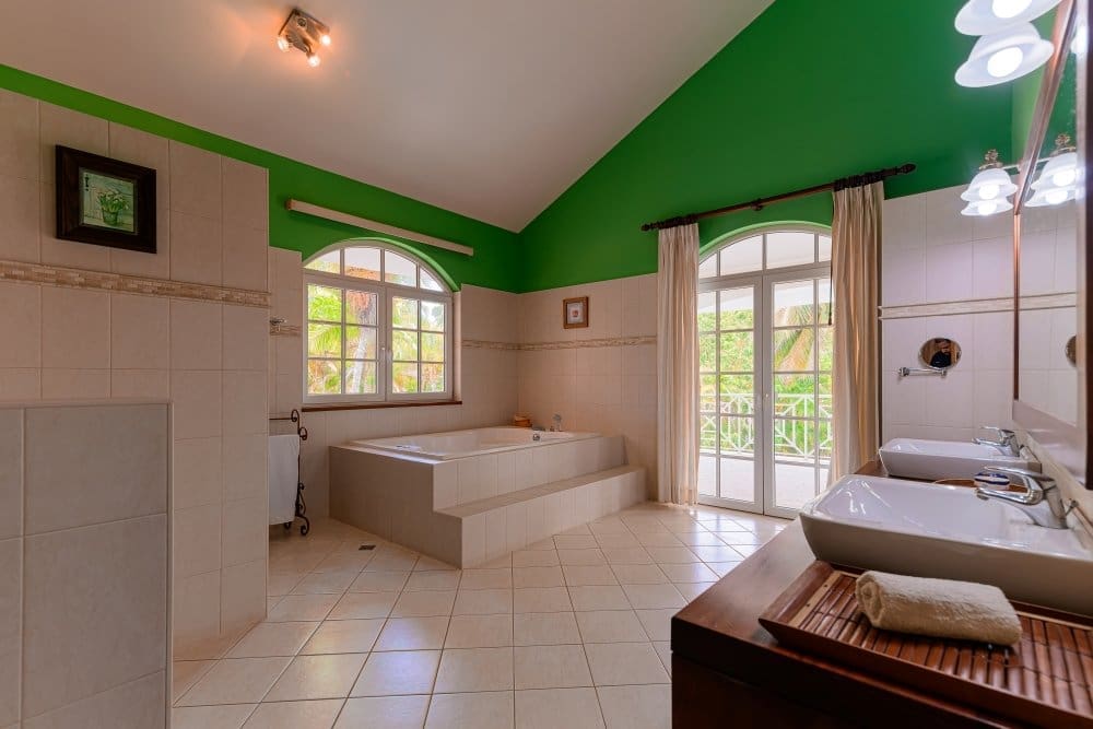 buyDRproperty Spacious bathroom with a large bathtub, double vanity, and green ceiling. Sosua Real Estate