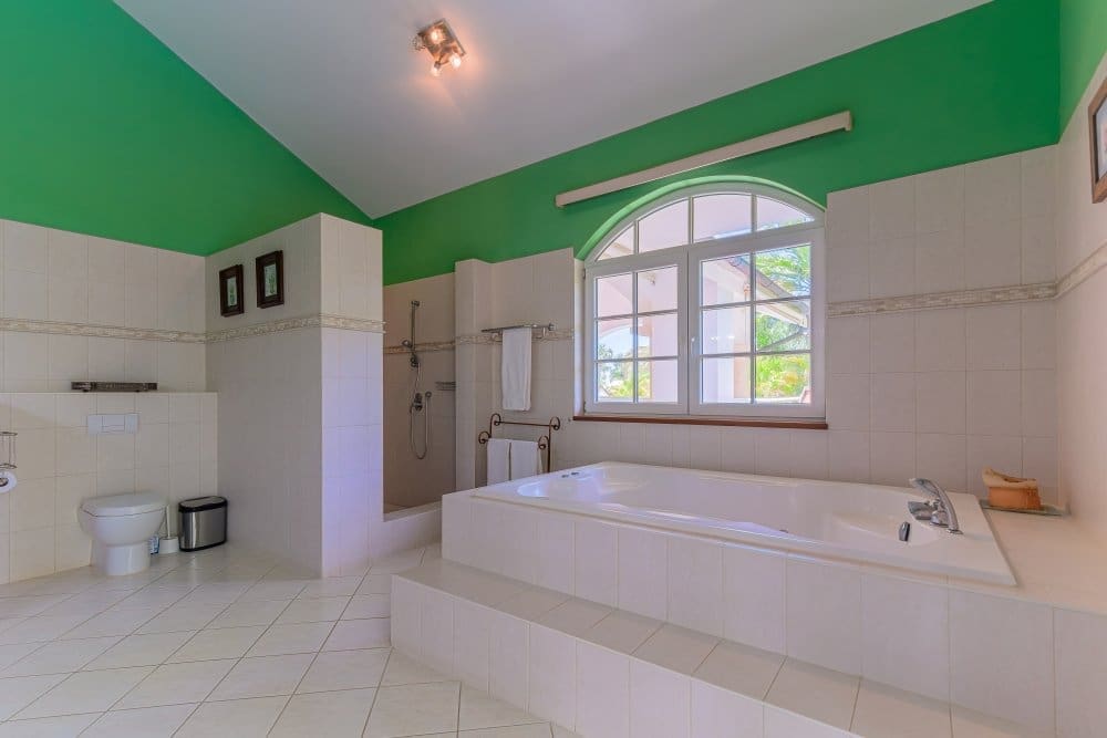buyDRproperty Spacious white bathroom with a large soaking tub and green ceiling Sosua Real Estate