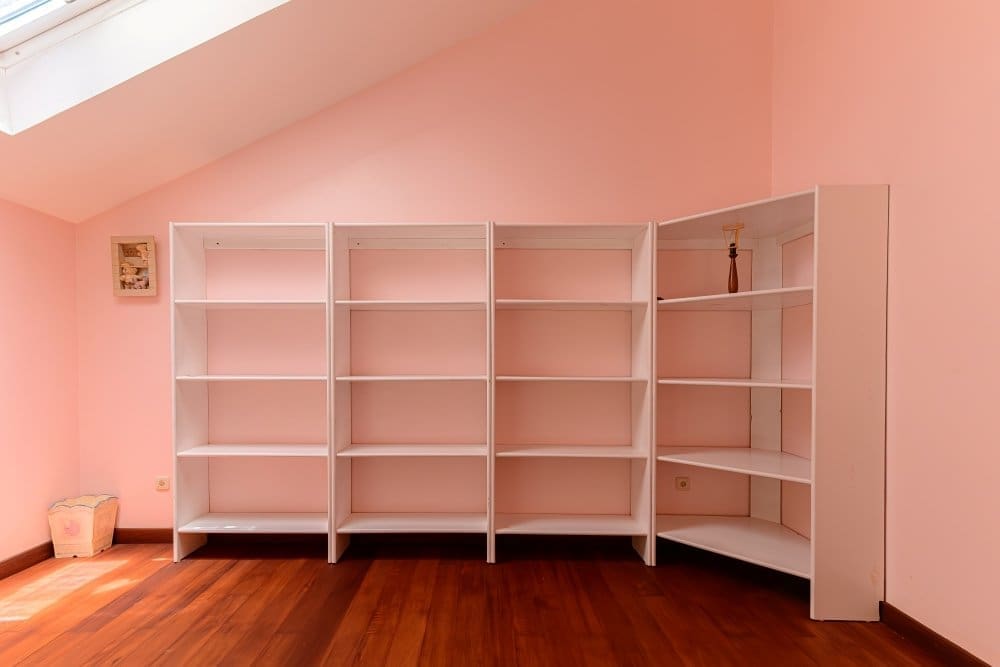 buyDRproperty Empty white bookshelves arranged in a corner against a pink wall Sosua Real Estate