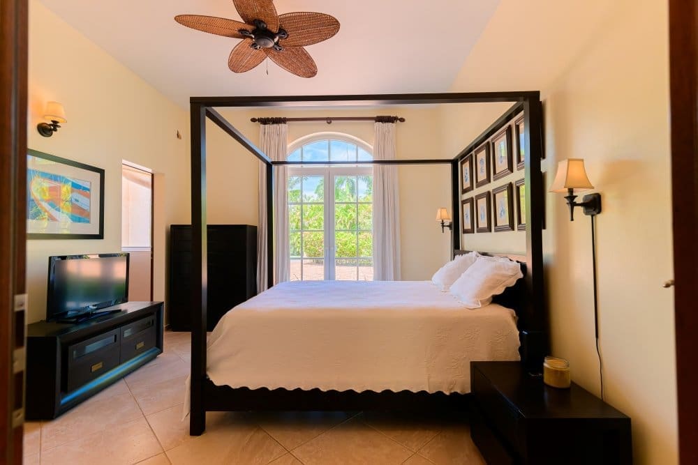 buyDRproperty Master bedroom with canopy bed, ceiling fan, and tropical garden view Sosua Real Estate