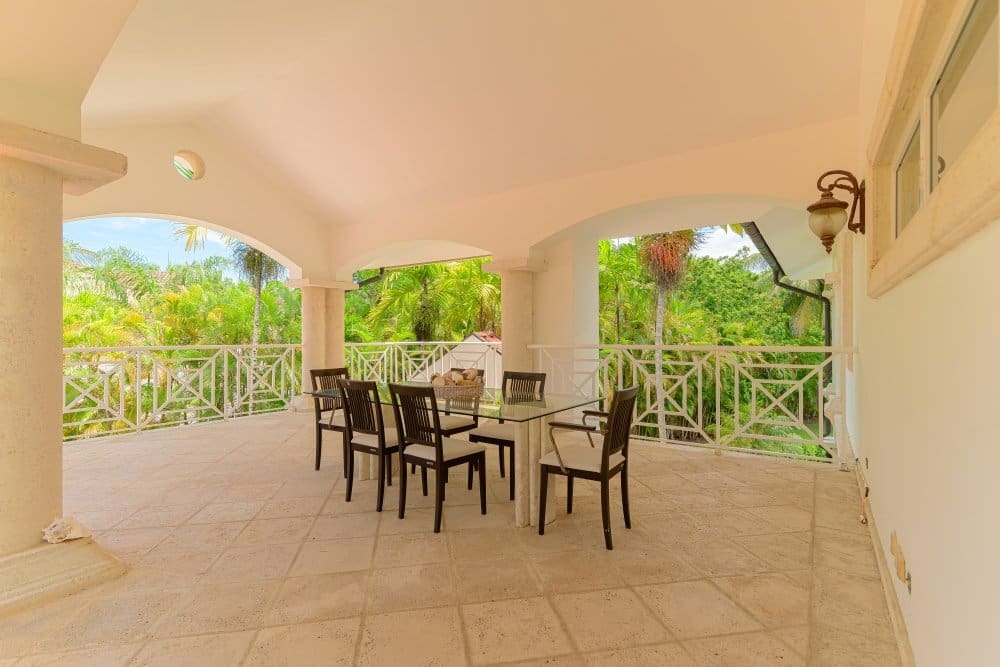 buyDRproperty Covered patio dining area with table and chairs overlooking lush tropical greenery. Sosua Real Estate
