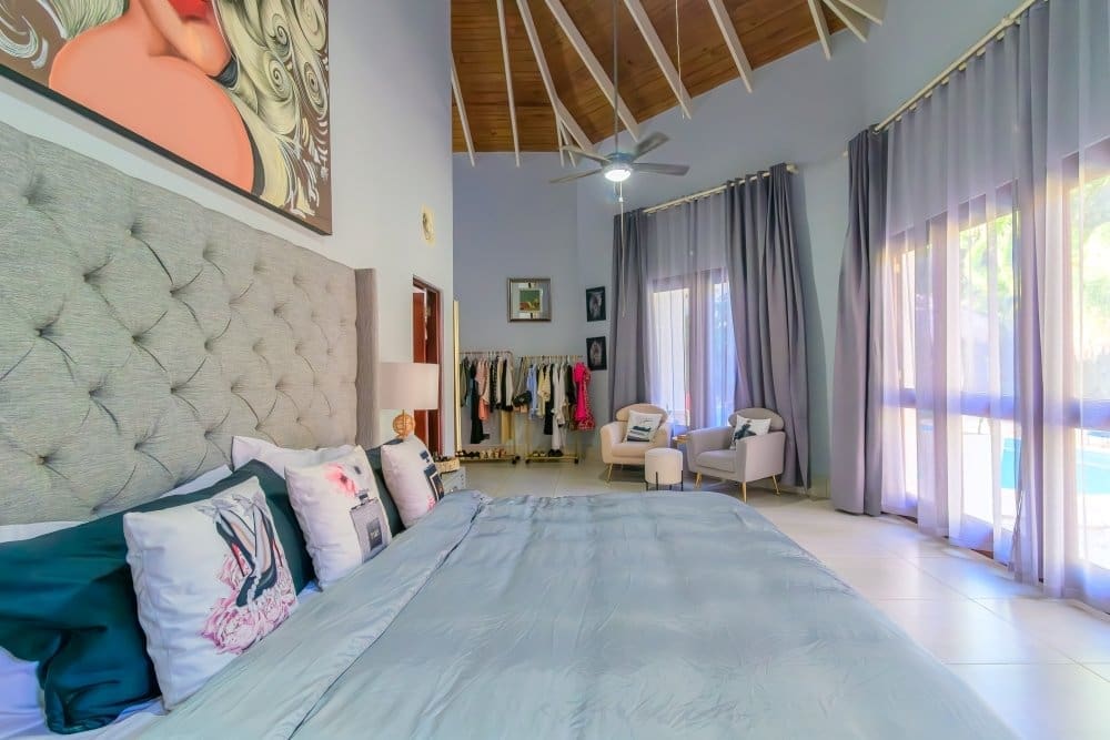 Spacious bedroom with a tufted gray headboard, light blue bedding, and decorative pillows.