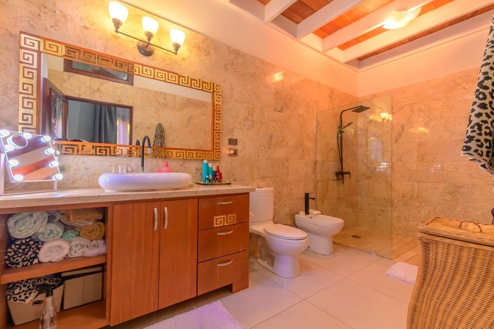 buyDRproperty Luxurious marble bathroom with a modern vanity, bidet, and glass-enclosed shower. Sosua Real Estate