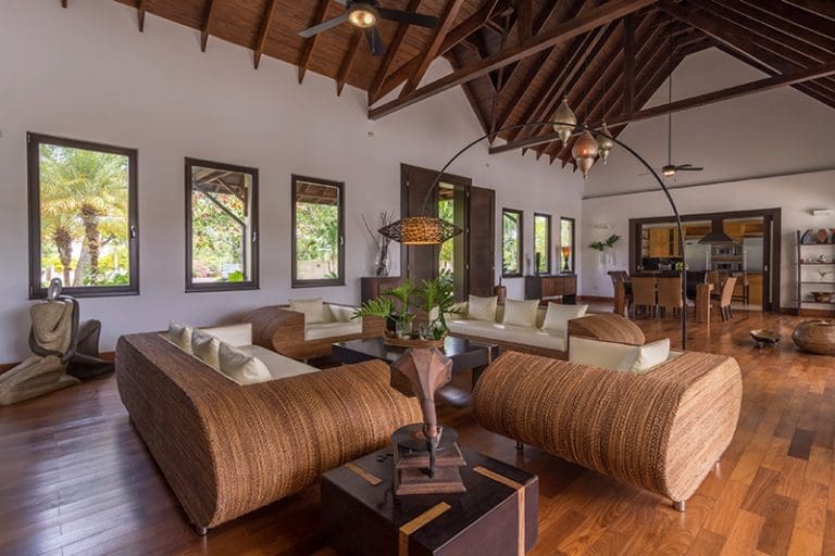 buyDRproperty Spacious living room with vaulted wood ceiling, rattan furniture, and large windows. Sosua Real Estate
