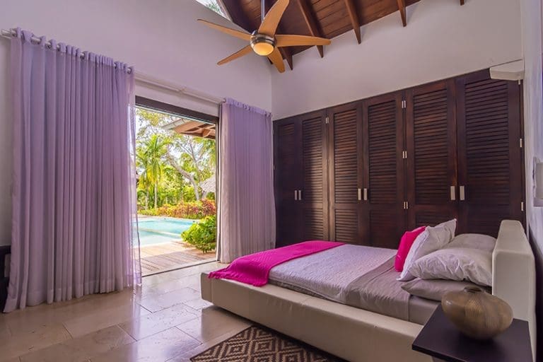 buyDRproperty Bedroom with pool view, wooden closets, and pink throw Sosua Real Estate