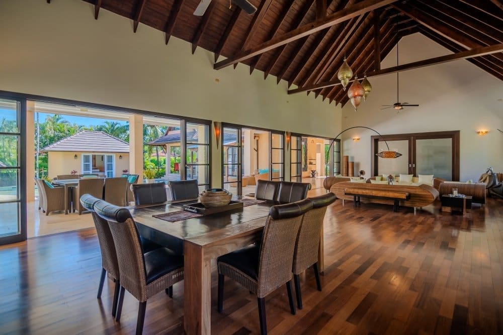buyDRproperty Spacious dining room with wooden table and chairs, opening to a tropical patio. Sosua Real Estate