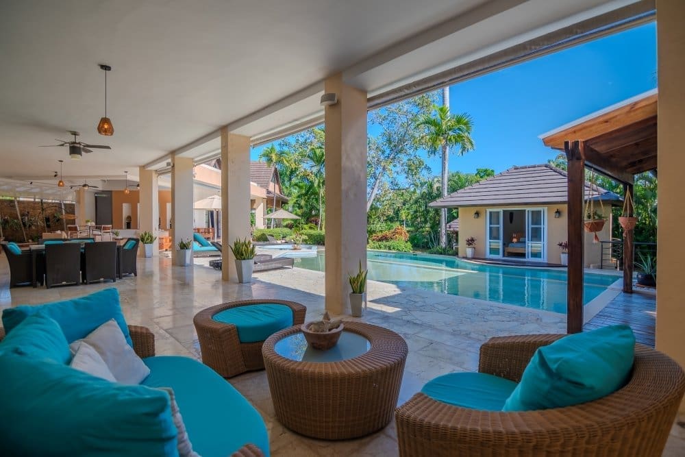 buyDRproperty Luxurious patio with turquoise seating overlooking a tropical pool and villa Sosua Real Estate