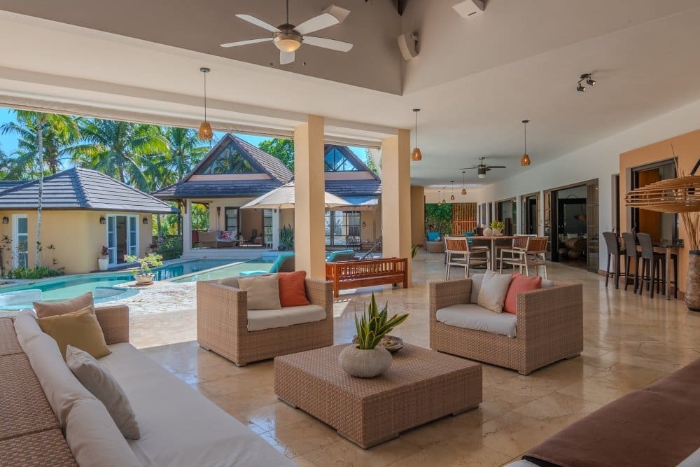 buyDRproperty Spacious, modern open-plan living area with rattan furniture and pool view Sosua Real Estate