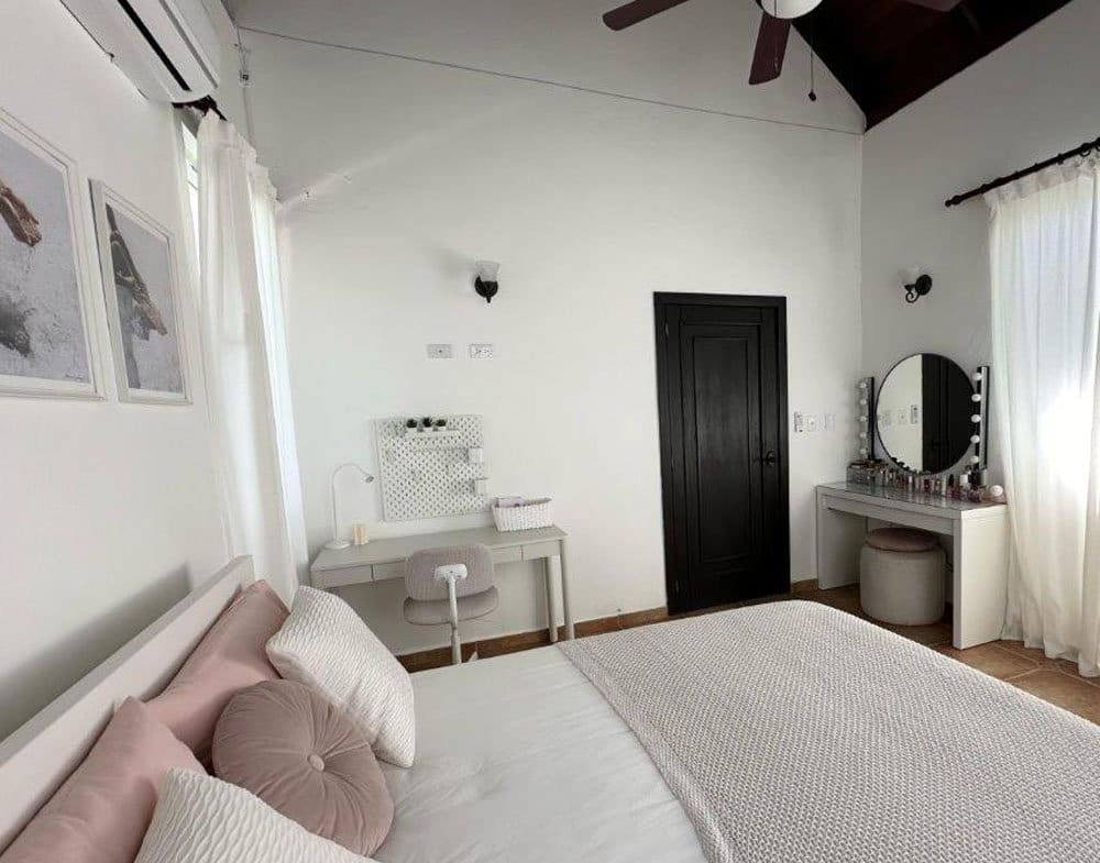buyDRproperty Bright bedroom with a white bed, vanity, and desk. Sosua Real Estate