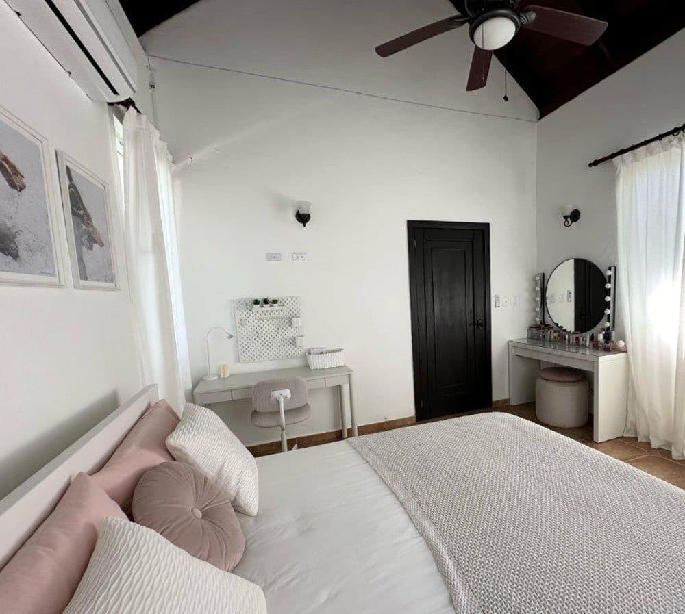 buyDRproperty Bright bedroom with a white bed, vanity, and desk. Sosua Real Estate