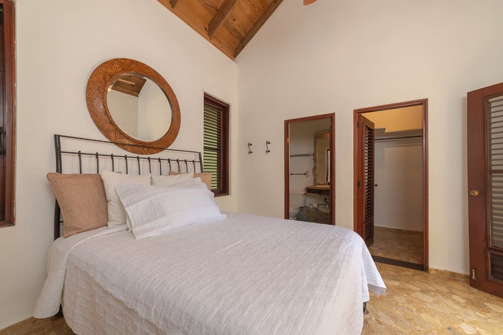 buyDRproperty Cozy bedroom with a queen bed, rustic mirror, and open closets Sosua Real Estate