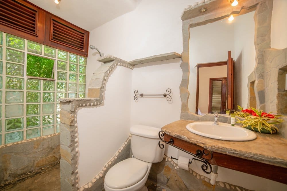 buyDRproperty Rustic bathroom with stone accents, glass block window, and unique sink vanity. Sosua Real Estate