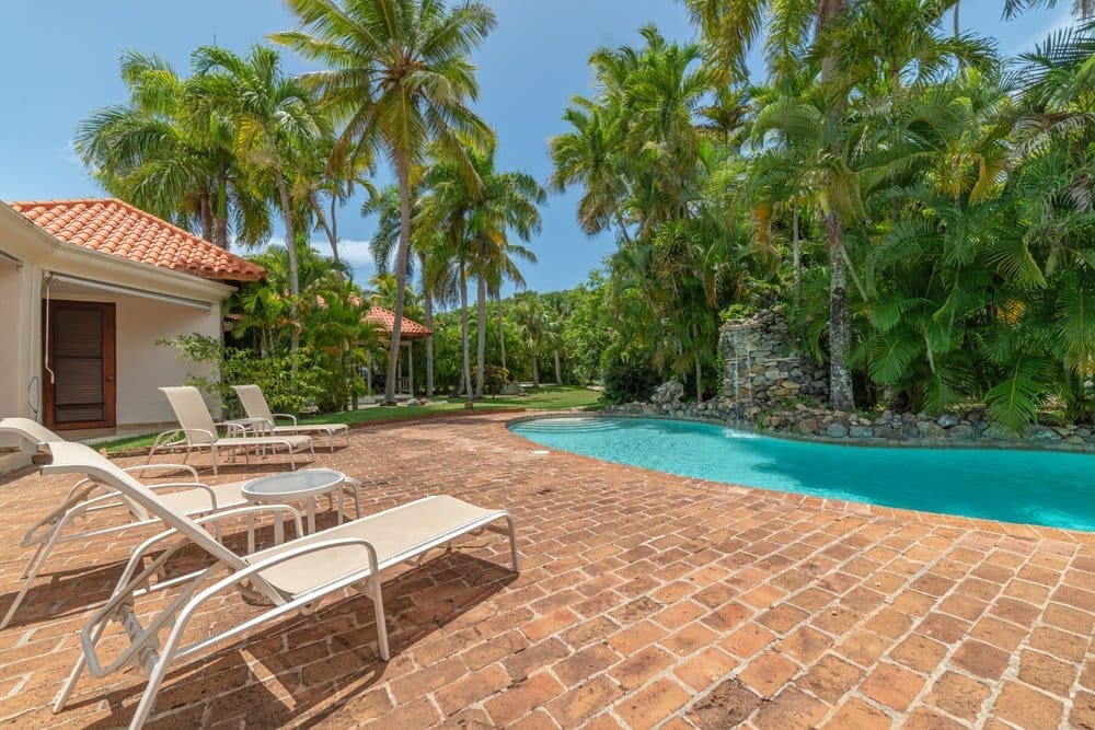 buyDRproperty Luxury villa with pool, lounge chairs, and palm trees in a tropical setting. Sosua Real Estate