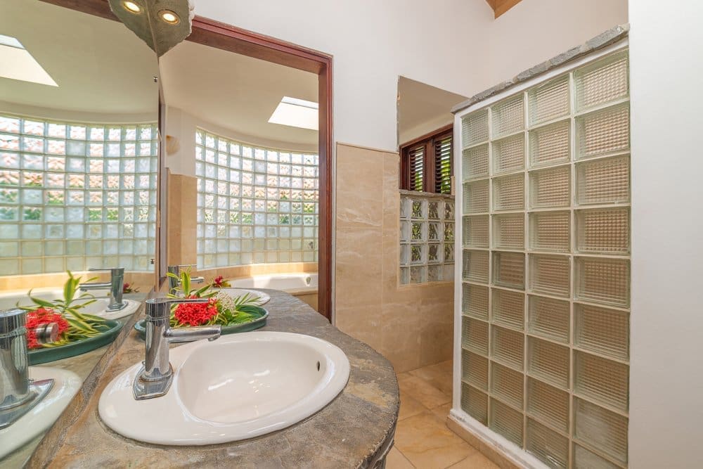 buyDRproperty Modern bathroom with double vanity, glass block shower, and skylight Sosua Real Estate