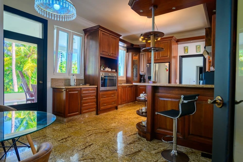 buyDRproperty Luxury kitchen with dark wood cabinets, granite countertops, and tropical outdoor view. Sosua Real Estate