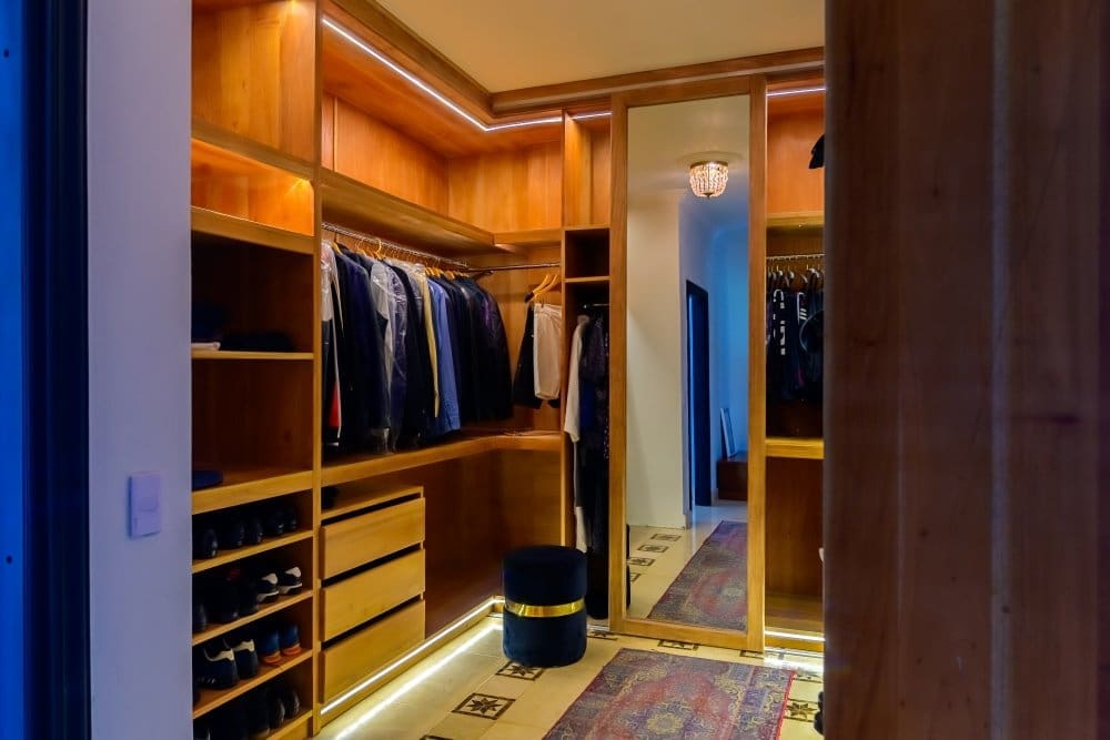 buyDRproperty Luxurious walk-in closet with custom wooden cabinetry, organized clothing, and ambient lighting. Sosua Real Estate