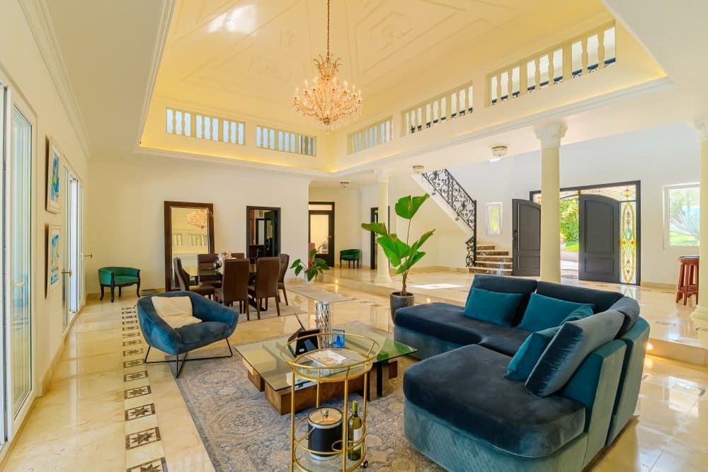 buyDRproperty Spacious modern living room with sectional sofa, chandelier, and grand staircase. Sosua Real Estate