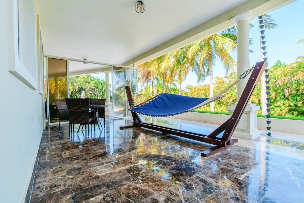 buyDRproperty Blue hammock on a marble patio with palm trees in the background Sosua Real Estate