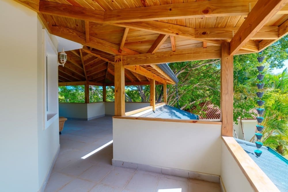 buyDRproperty Wooden covered balcony with tropical trees and chain rain gutter Sosua Real Estate