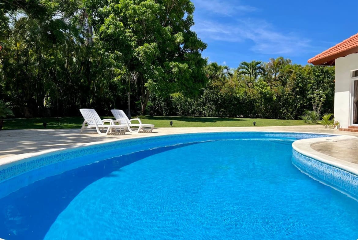 buyDRproperty Sunny swimming pool with lounge chairs in a lush tropical garden Sosua Real Estate