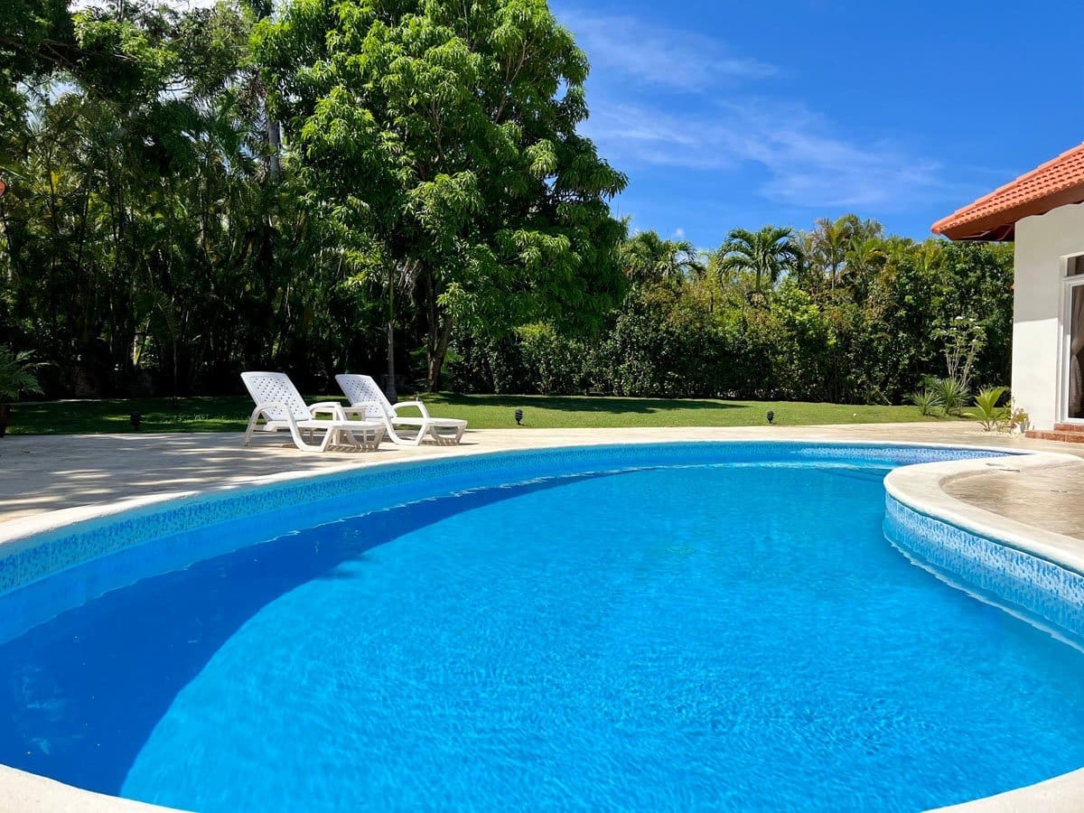 buyDRproperty Sunny swimming pool with lounge chairs in a lush tropical garden Sosua Real Estate