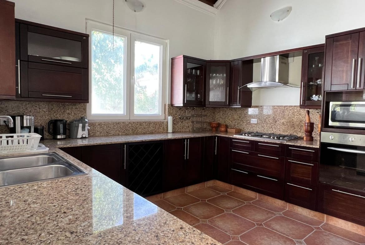 buyDRproperty Spacious dark wood kitchen with granite countertops and stainless steel appliances. Sosua Real Estate