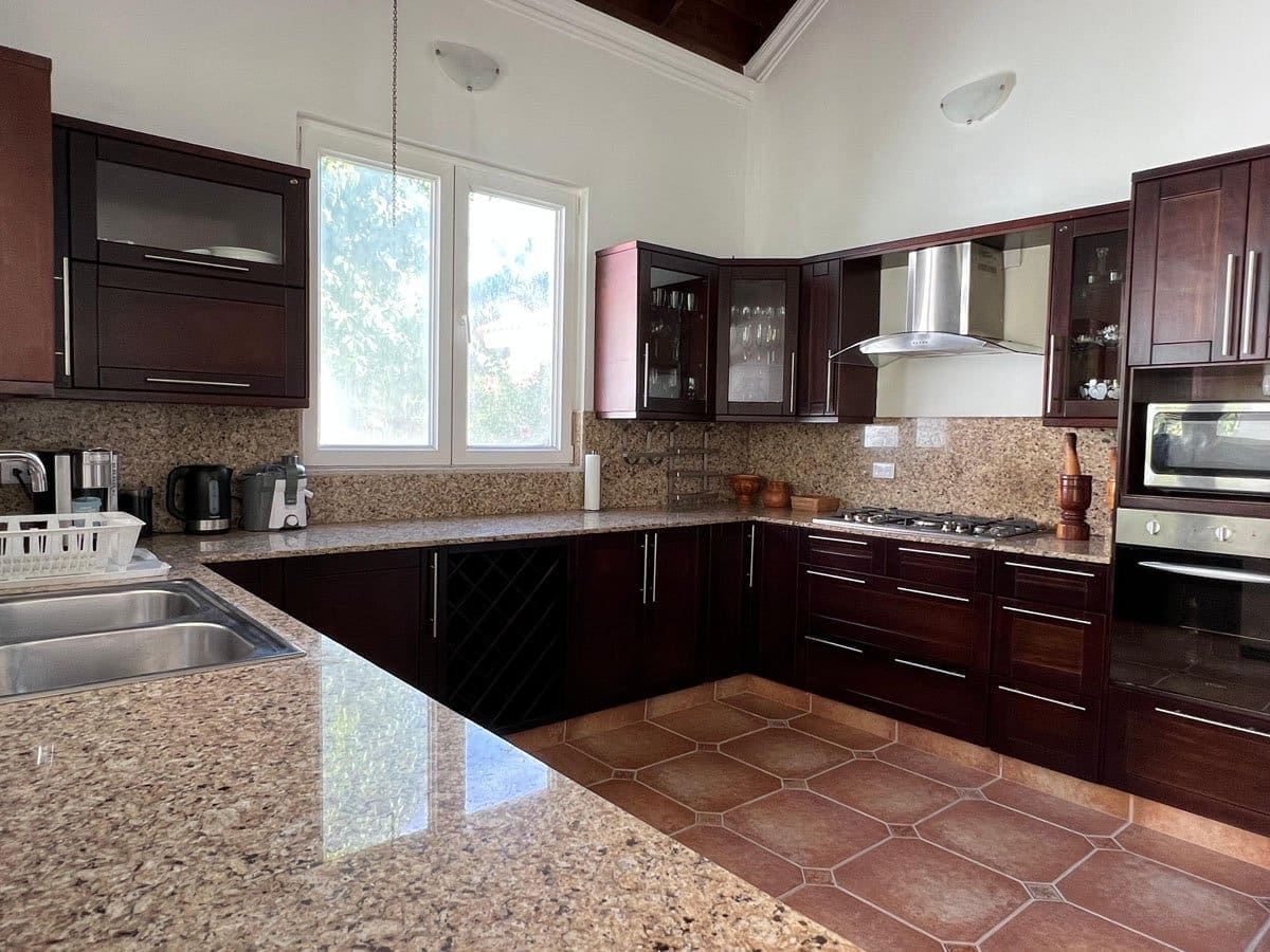 buyDRproperty Spacious dark wood kitchen with granite countertops and stainless steel appliances. Sosua Real Estate