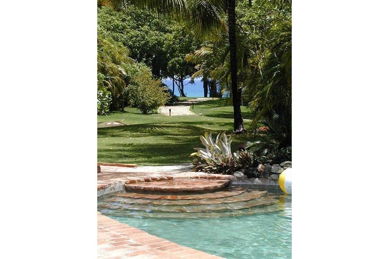 buyDRproperty Tropical pool steps leading to lush garden and ocean view Sosua Real Estate