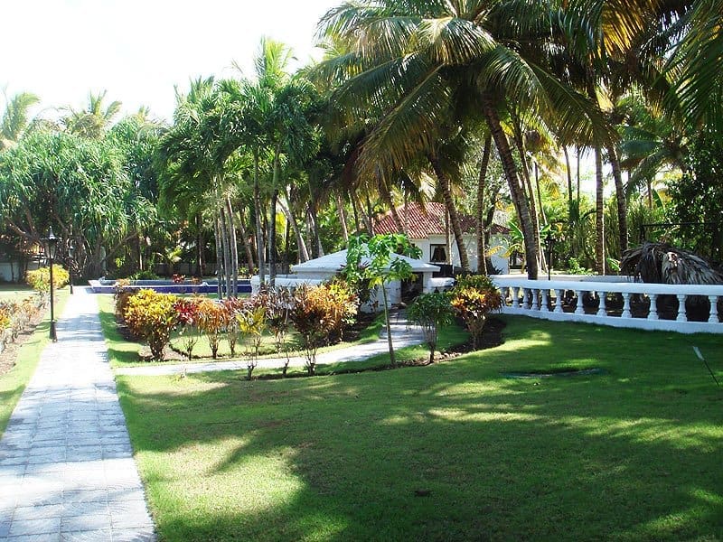 buyDRproperty Tropical resort garden with palm trees, pool, and white building Sosua Real Estate
